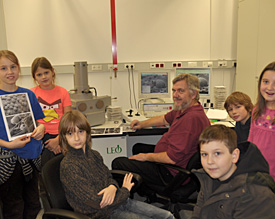 Dr. Linne von Berg (Bildmitte) demonstriert Josi, Lea, Adrian, Noel, Tom und Lillian ein Rasterelektronenmikroskop