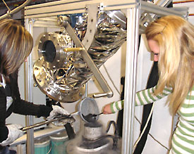 Carolin Schumacher (l.) und Miriam Latuske füllen das Kometen-Rohmaterial in die Carolin Schumacher (l.) und Miriam Latuske füllen das Kometen-Rohmaterial in die Simulationskammer