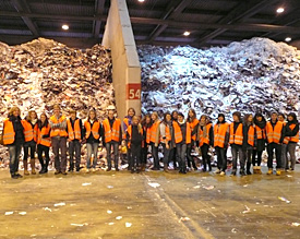 Der Biochemie-Kurs der Stufe 9 mit Lehrerin Sabine Staas in kleidsamer Besucherweste vor gewaltigen Bergen Altpapier